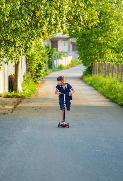 The child is riding a scooter down the street. Selective focus.