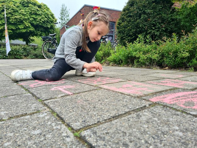 子供がチョークで歩道に立っています。