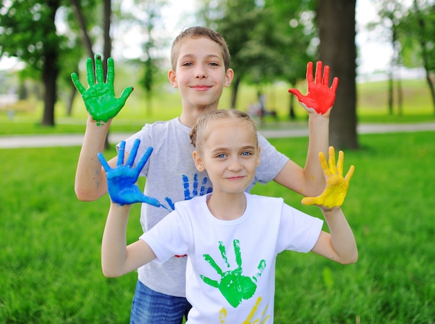 The child is smeared with brightly colored finger paints clothes smiling in the Park.