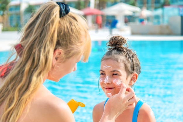 The child is smearing sunscreen on the mother