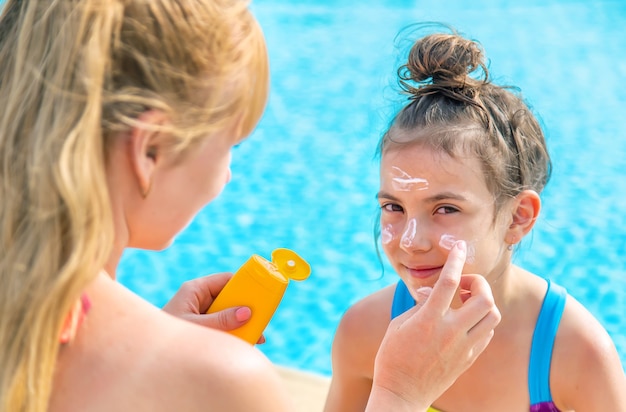 The child is smearing sunscreen on the mother