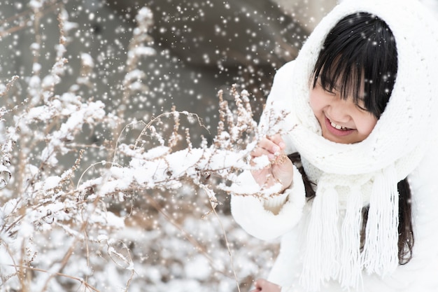 The child is smiling brightly at the snow falling on the tree