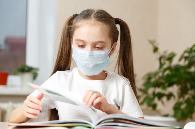 The child is studying at home, studying at home during quarantine, masked child studying at home