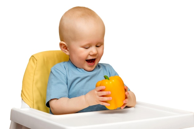 The child is surprised and rejoices in the yellow sweet pepper healthy food