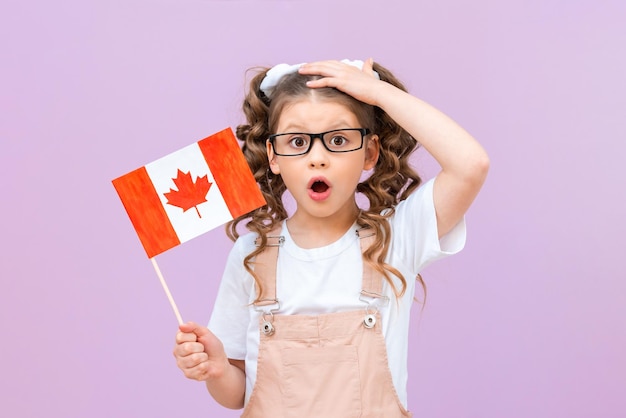 The child is surprised that he will study in Canada A little girl holds a Canadian flag Education of children under the exchange program