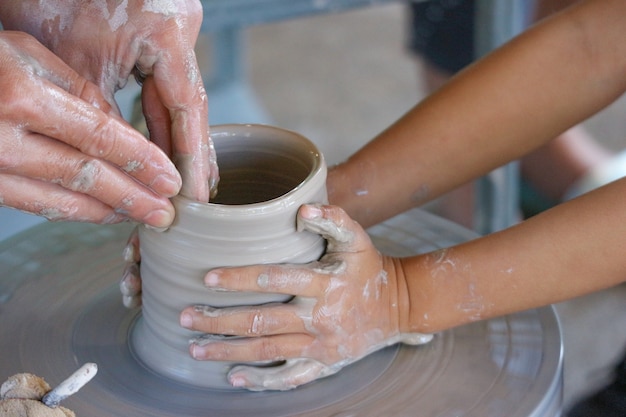 A child is training how to pot a ceramic vase with teacher