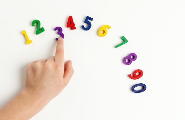 The child is using the index finger to move the number three upwards Early education Learning colors and to count from zero to ten