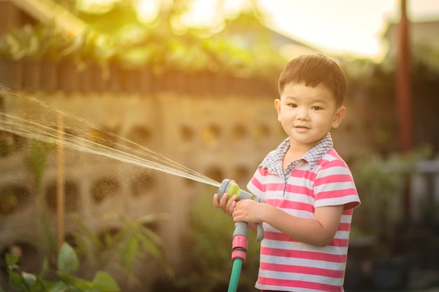 子供は自宅で鉢植えに水を注いでいます。