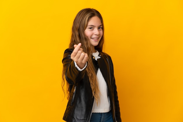 Child over isolated yellow background making money gesture