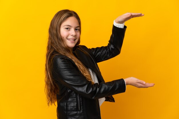 Ребенок над изолированной желтой стеной, отображающей copyspace, чтобы вставить рекламу