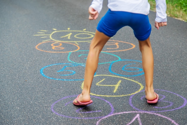 Photo child jumping classics on the pavement. selective focus.