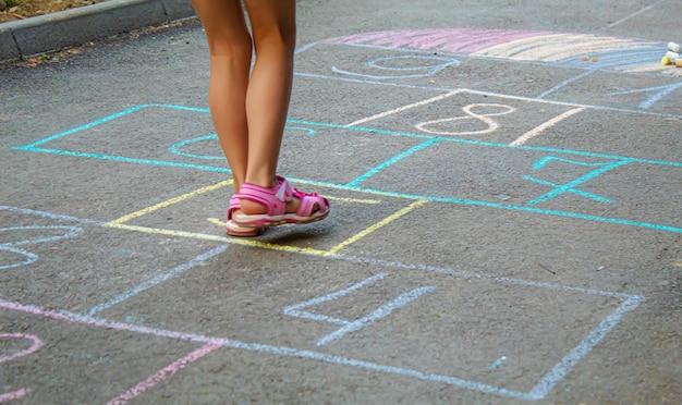 Child jumping classics on the pavement. Selective focus.