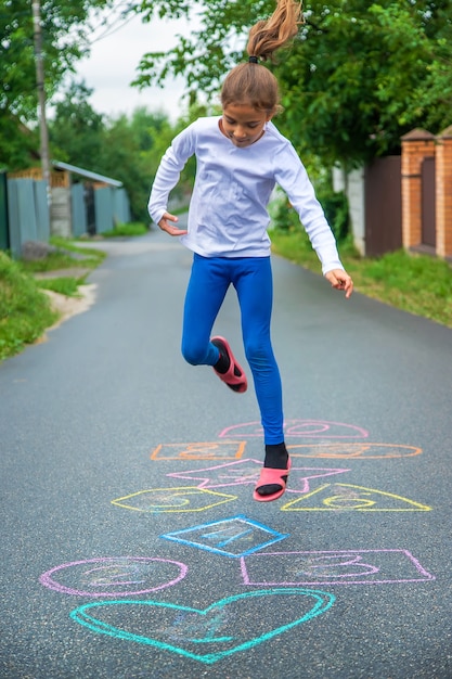 路上でクラシックをジャンプする子供。セレクティブフォーカス。