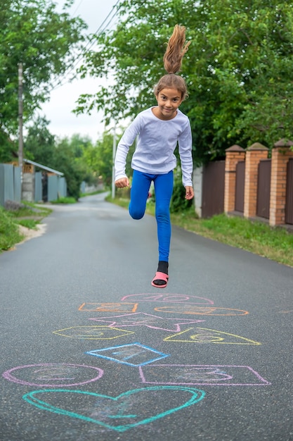 Child jumping classics on the street. Selective focus.