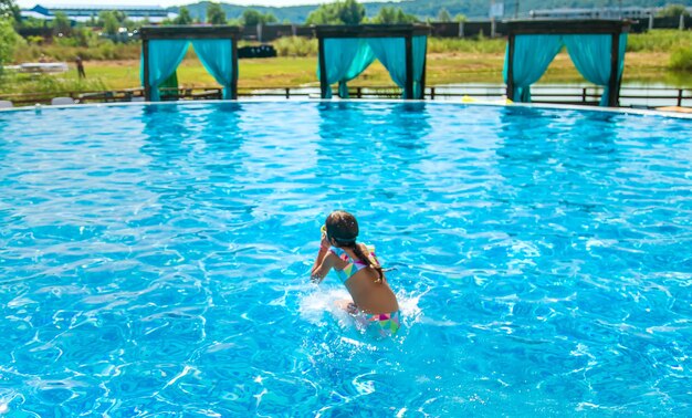 Foto il bambino salta si tuffa in piscina. messa a fuoco selettiva. ragazzo.