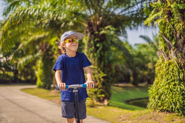 公園の子供たちのキックスクーターの子供は晴れた夏にスケートローラーボード小さな男の子をスケートすることを学ぶ