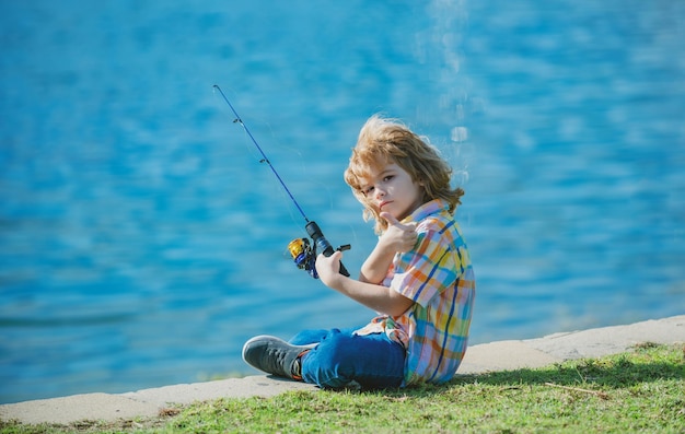 Child kid fisher boy with spinner at river little boy fishing boy at jetty with rod fishing concept