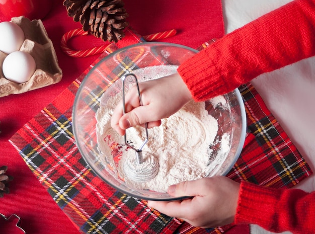 Child kid making dough for Christmas cookies kitchen utensil and ingredient on the wooden background Top view Copy space