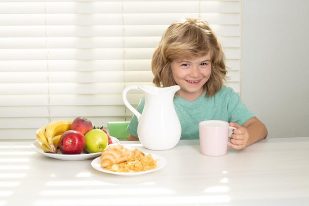 Child in the kitchen at the table eating vegetable and fruits during the dinner lunch healthy food v