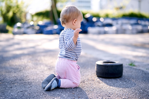 子供が駐車場の車の縁の近くにひざまずく