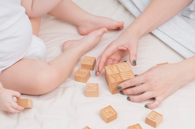 아이는 나무 큐브 클로즈업으로 만든 장난감이라는 단어를 배치했습니다. 작은 아이는 영어 알파벳을 읽는 법을 배웁니다. 유아 발달 교육 게임