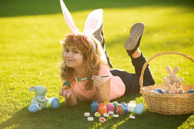 Child laying on grass in park wit easter eggs children celebrating easter painting eggs kid in rabbi