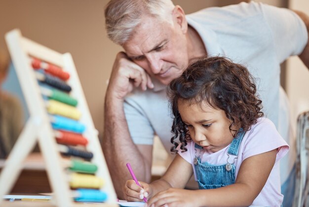 Child learning and father teaching with abacus together for development Elderly man grandparent or teacher with young student girl writing in book for education or study skills activity at home