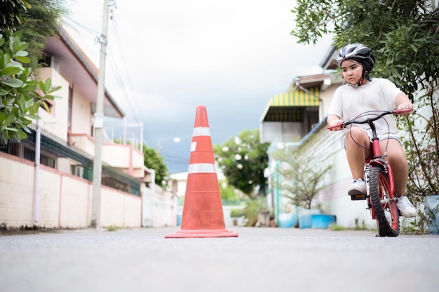 自転車に乗ることを学ぶ子供は、トラフィックコーンの周りに乗ることを練習することによって