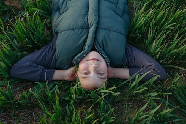 Photo a child lies on the grass and looks up at the camera.