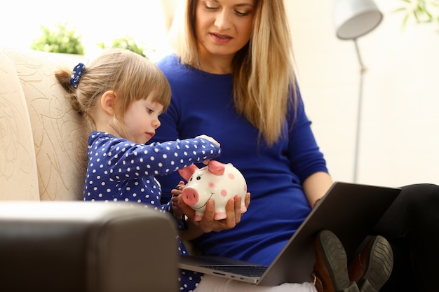 Child little girl arm putting coin in piggybank