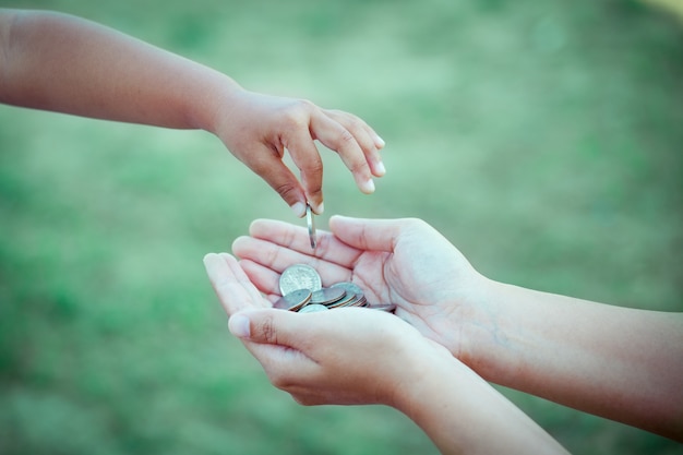 child little girl giving coin to mother as saving money concept in vintage color tone