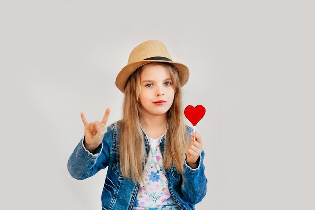 Child, little girl holding heart shaped candy, isolated on white background.