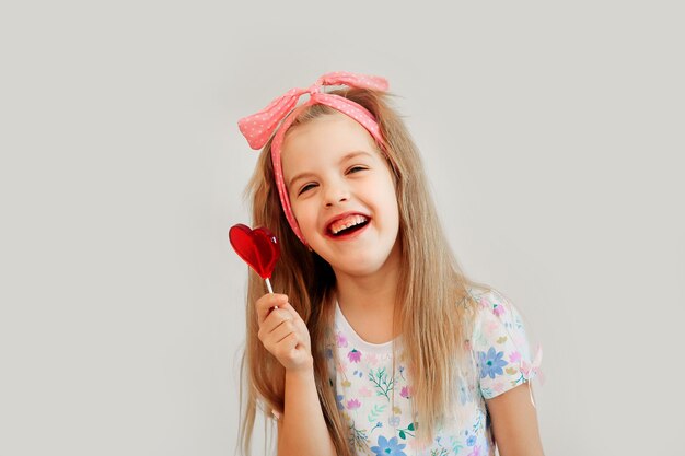 Child, little girl holding heart shaped candy, isolated on white background.