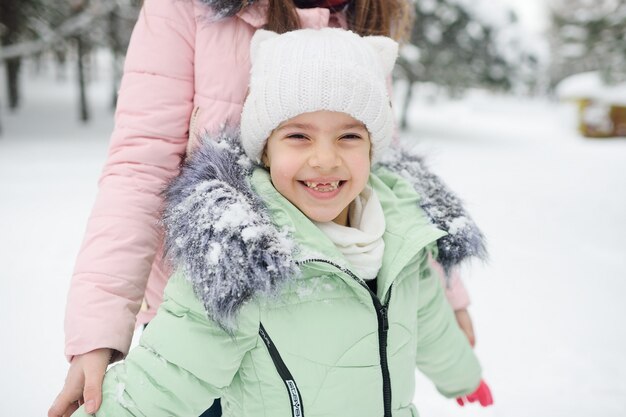 子雪の背景に笑みを浮かべて暖かい冬の服の少女。冬のエンターテイメント