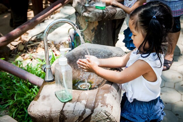 Child little girl washing her hand in park