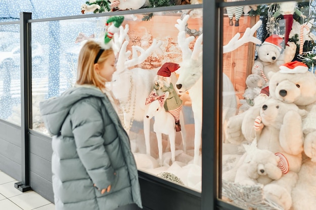 Foto un bambino guarda una vetrina con i giocattoli per natale