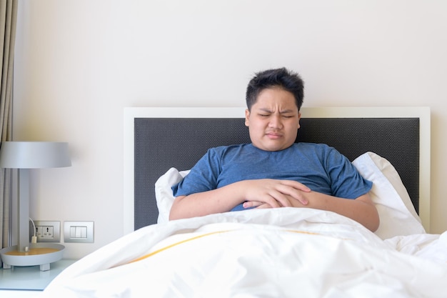 Child lying on bed in the living room with stomach pain Hands on belly