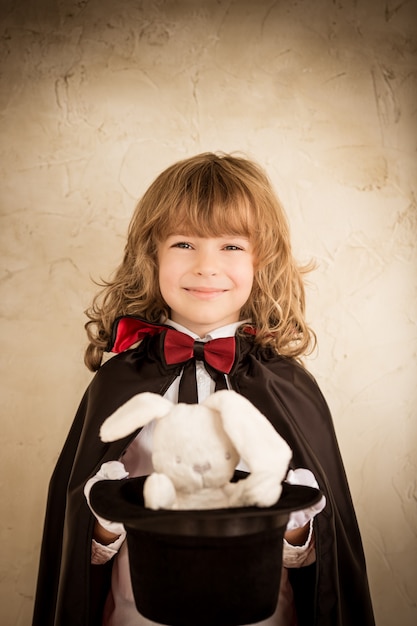 Child magician holding a top hat with a toy rabbit. Success concept