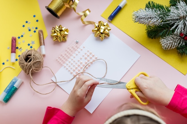 Photo child makes a christmas card for the winter holidays. diy crafts and crafts for christmas do-it