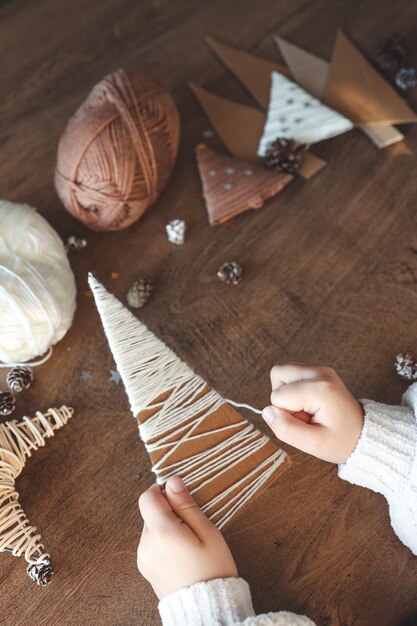 Foto bambino fa una decorazione natalizia con il filato