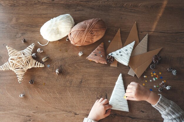 Photo child makes christmas decoration from yarn