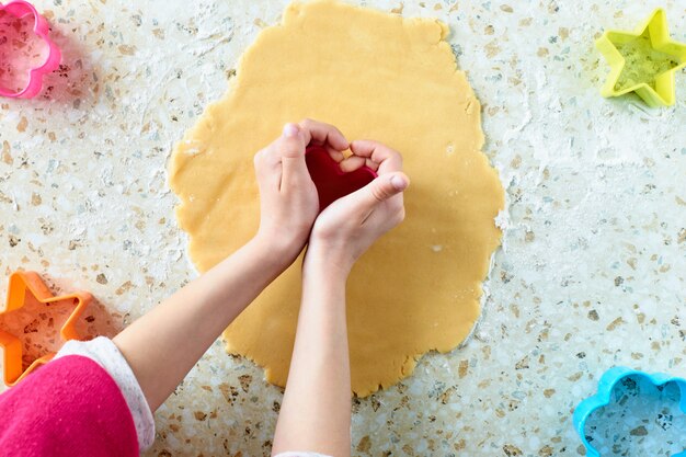 A child makes cookies, rolls out the dough and uses forms to make cookies.