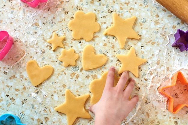 子供はクッキーを作り、生地を伸ばし、フォームを使用してクッキーを作ります。