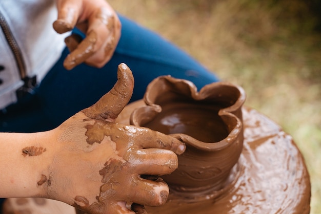 A child makes a jug of clay on a potter's wheel.