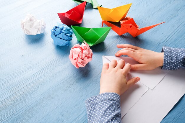 Foto il bambino fa origami su un tavolo blu