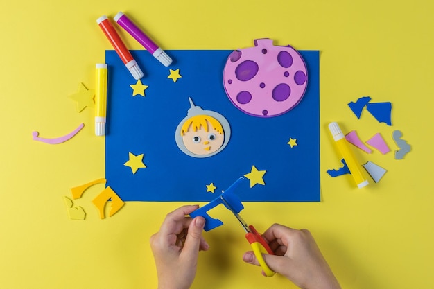 A child makes a picture out of paper on the theme of space