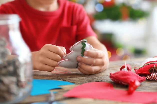 Child making felt Christmas fir tree at table