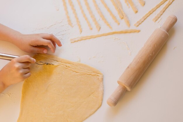 Child making homemade pasta at kitchen