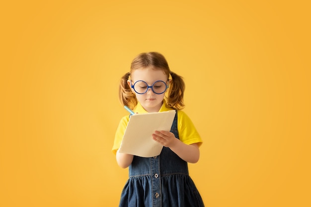 Child making notesKids dreams Isolated on yellow background Education background Kid back to school