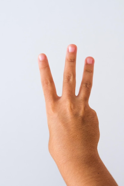 Child making number three sign on a white background